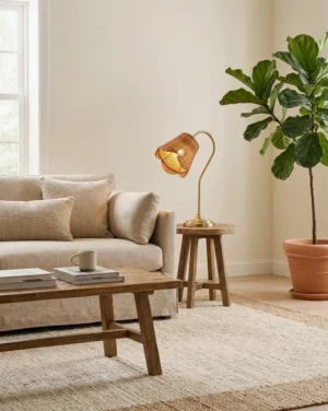Rattan gooseneck table lamp placed on side table in modern rustic living room with sofa and coffee table