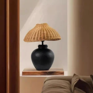 Modern rattan table lamp displayed on living room recessed shelf, showing natural rattan weave and black wooden base