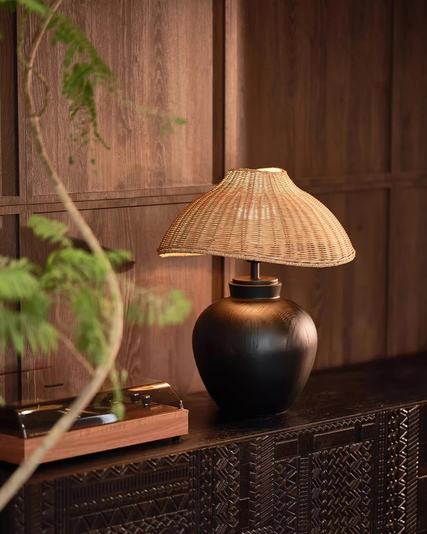 Natural rattan table lamp with matte black base on wooden cabinet with potted plants, eco-friendly design