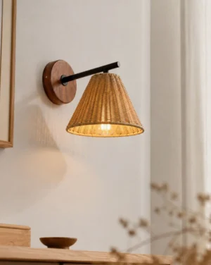 Rattan wall sconce three-quarter angle view in minimalist interior, showing tapered woven shade and metal arm detail