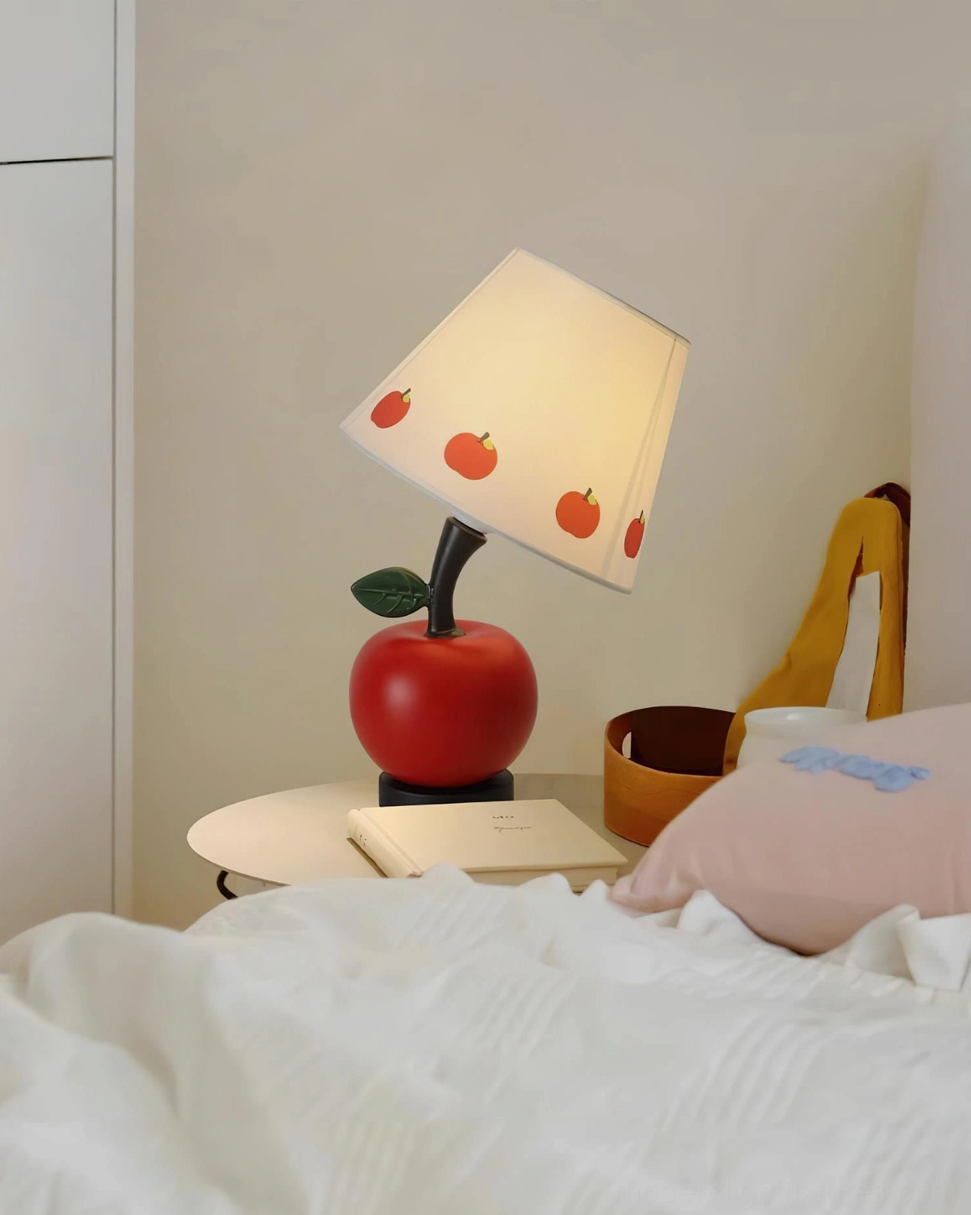 Red apple table lamp placed on bedroom nightstand with warm ambient lighting, bedside décor setup