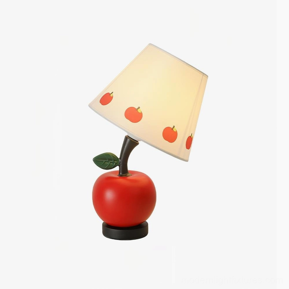 Red apple-themed table lamp with fabric shade showing fruit illustration details, studio background
