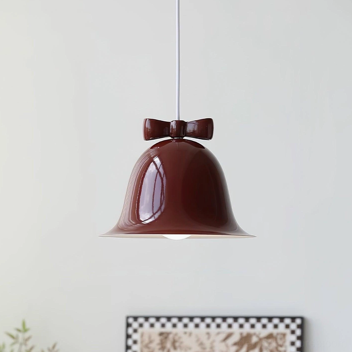 Rich red ceramic bell-shaped pendant lamp with matching bow ornament studio background