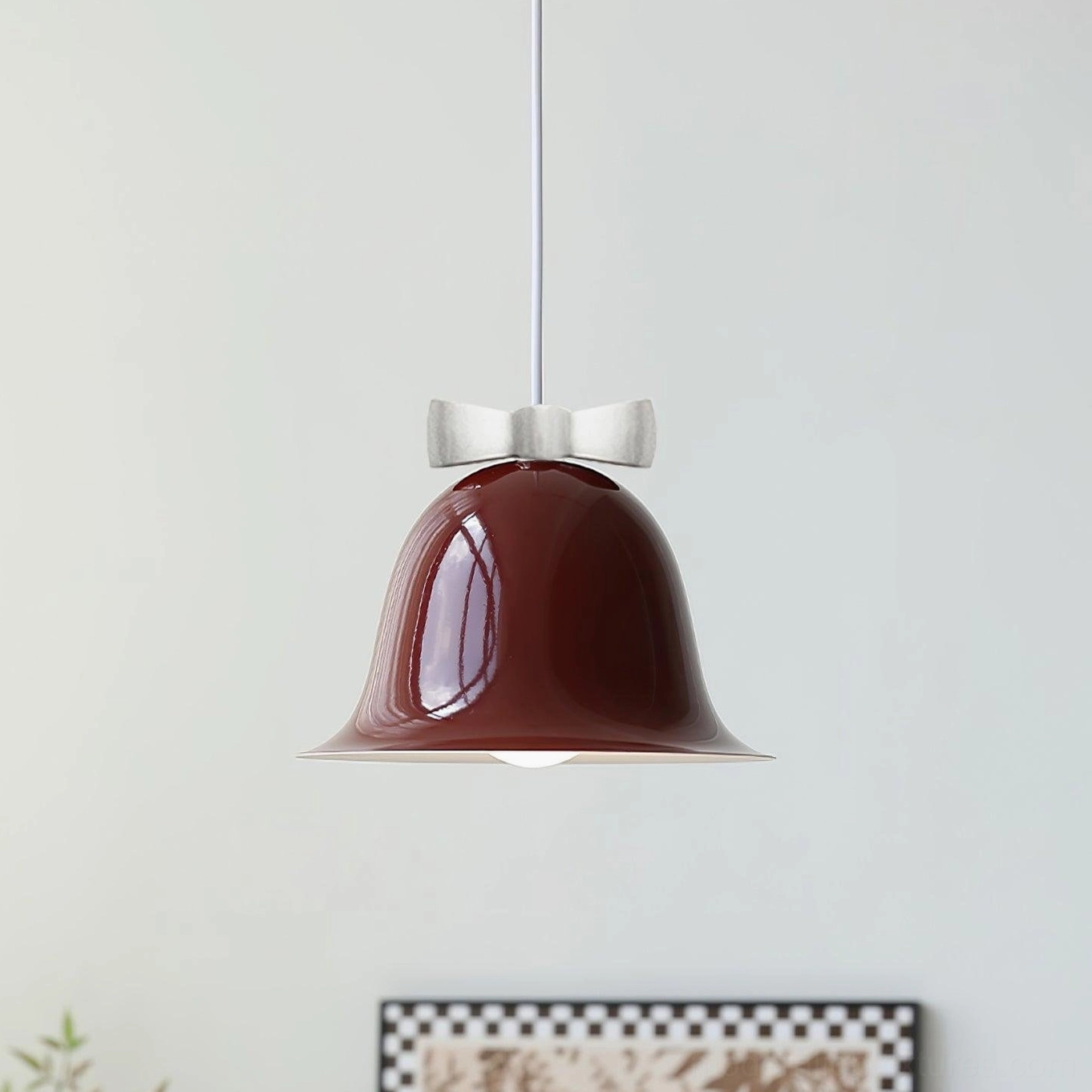 Red ceramic bell-shaped pendant light hanging in warm home interior accent lighting scene