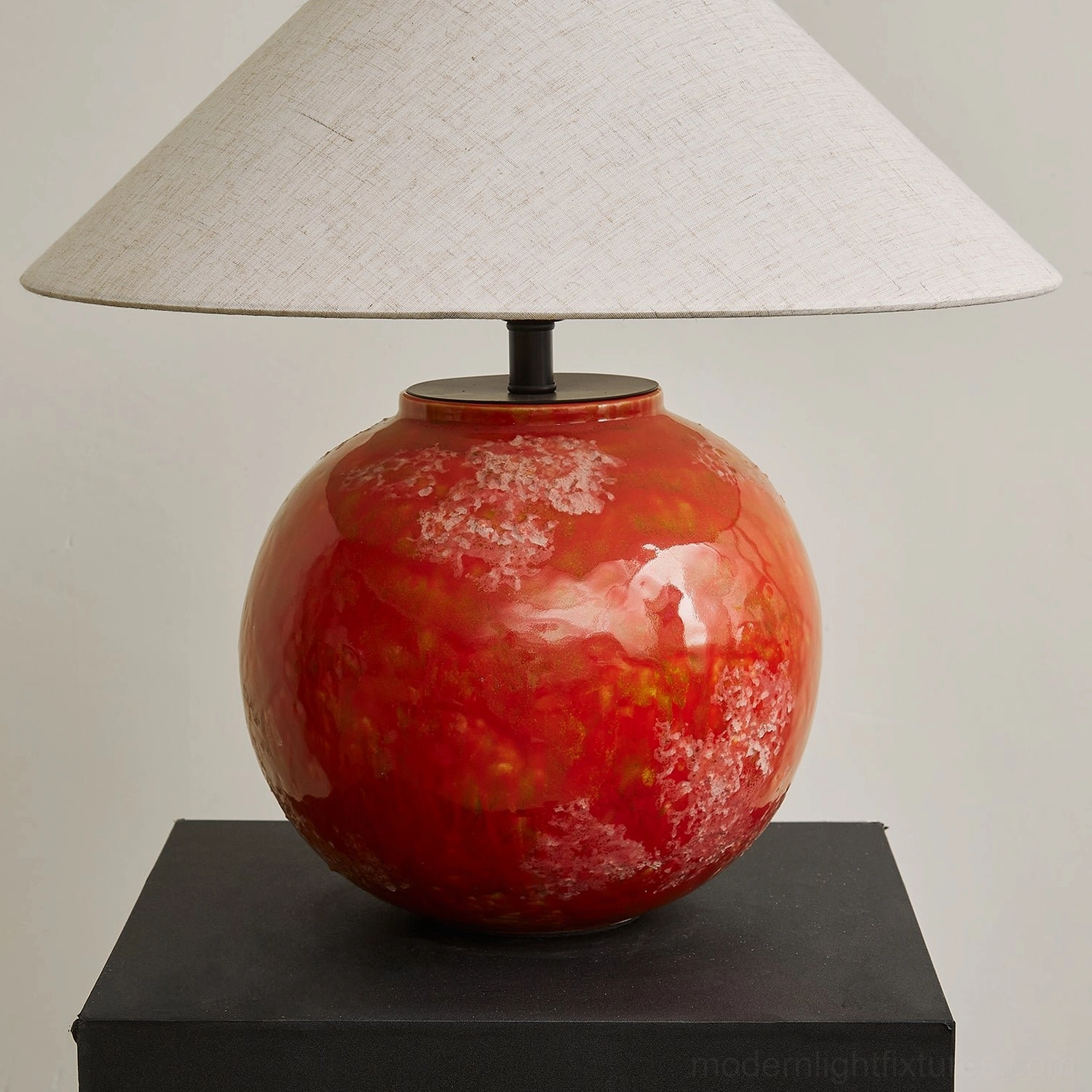 Close-up detail of red marbled glossy ceramic lamp base with wide flared linen lampshade, studio focus shot