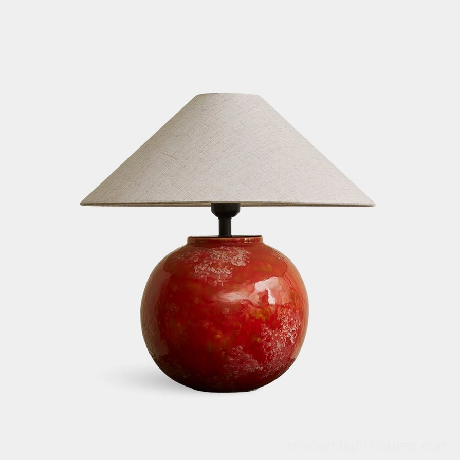 Modern red ceramic table lamp with marbled glossy finish and neutral linen conical shade, front studio view