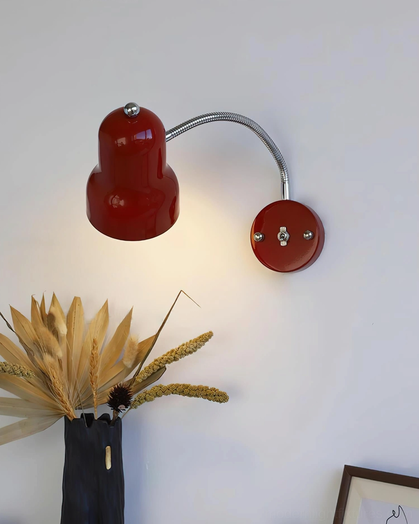Red wall-mounted sconce with polished chrome accents and warm ambient glow in styled room
