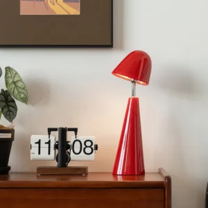 Red geometric cone table lamp with three-color LED displayed on wooden dresser with retro clock and plant decor