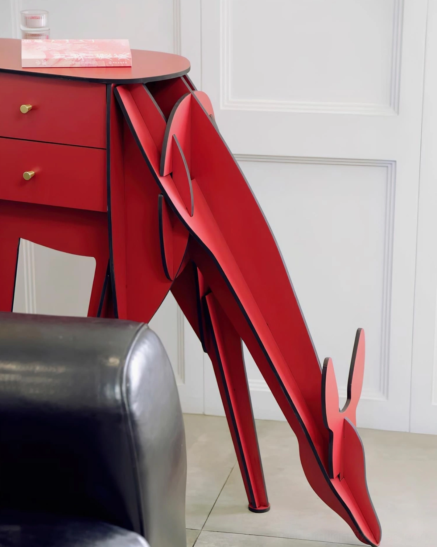 Red deer-shaped floor lamp close-up side angle, matte finish detail with leather sofa nearby, modern home interior