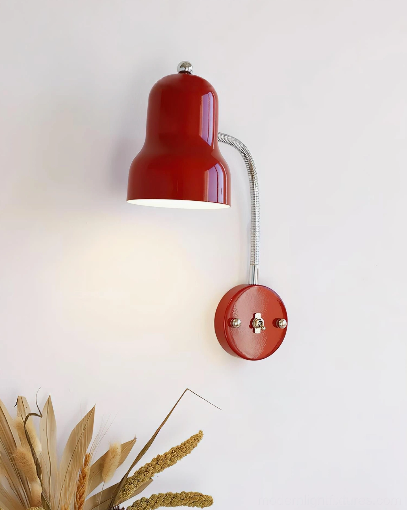 Red industrial wall sconce with flexible arm mounted on interior wall with botanical styling