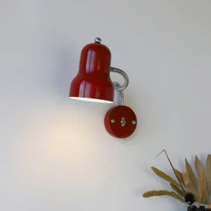 Red wall sconce mounted on interior wall with warm ambient lighting and vintage dried floral decor