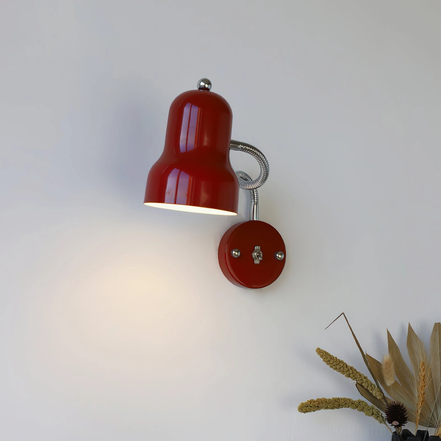Red wall sconce mounted on interior wall with warm ambient lighting and vintage dried floral decor