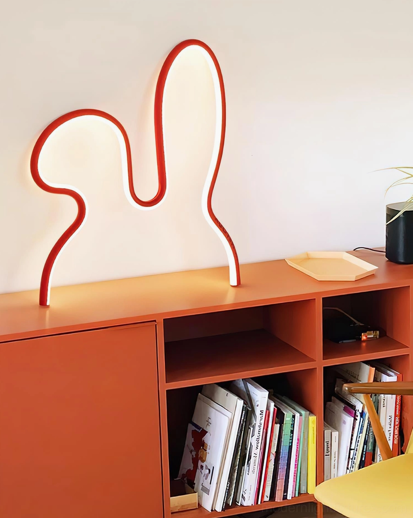 Red rabbit LED table lamp side view on home bookshelf with books and plants interior styling