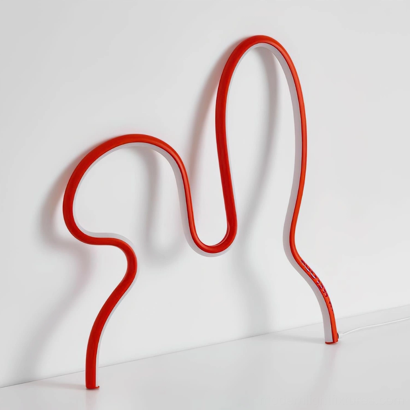 Red rabbit lamp leaning against white wall with light floor low angle studio view