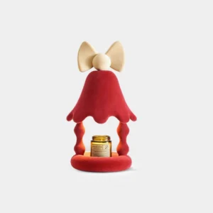 Red Stacy candle warmer table lamp with flocked resin body and bow top, displayed on white studio background, holding scented candle jar