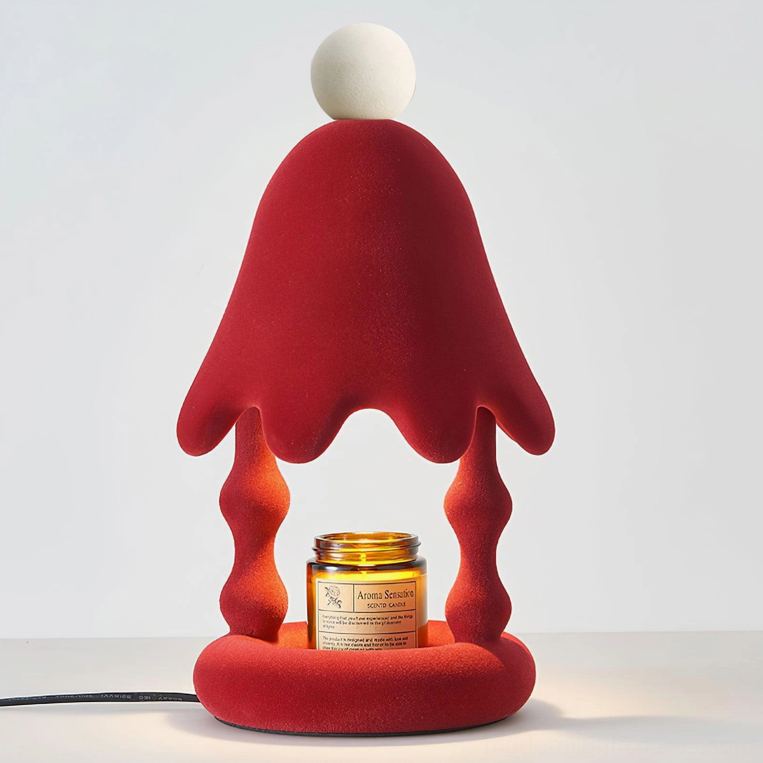 Red Stacy candle warmer table lamp three-quarter front view with visible power cord and scented candle jar, studio background