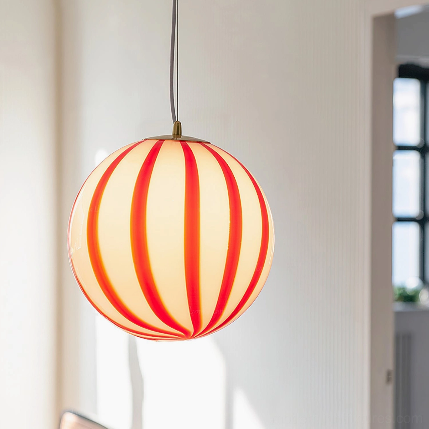 Lit red striped spherical pendant light casting warm yellow glow in modern living room