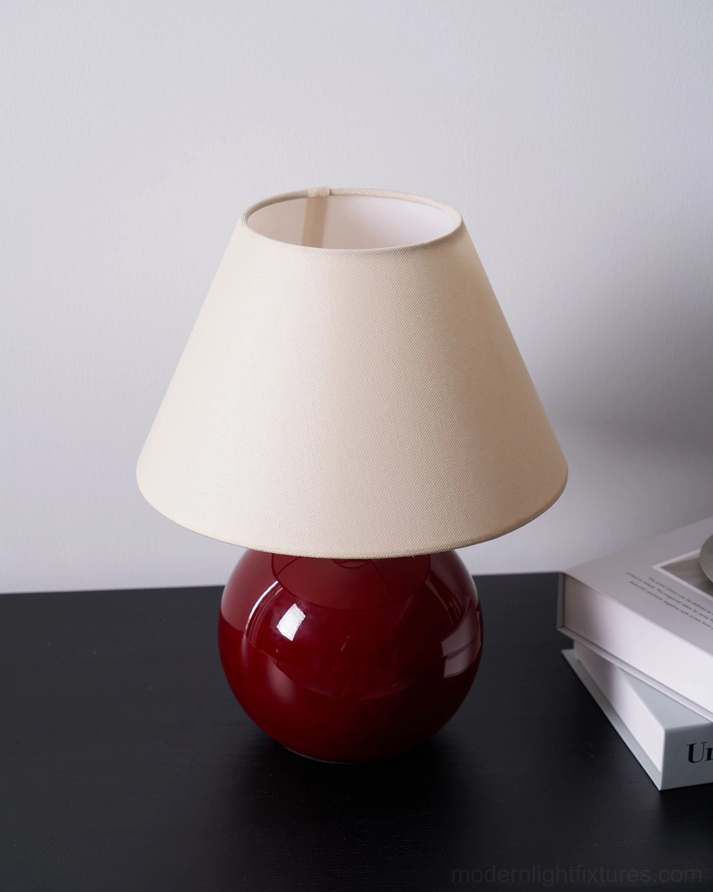 Red glass base table lamp with warm ambient lighting through cream fabric shade