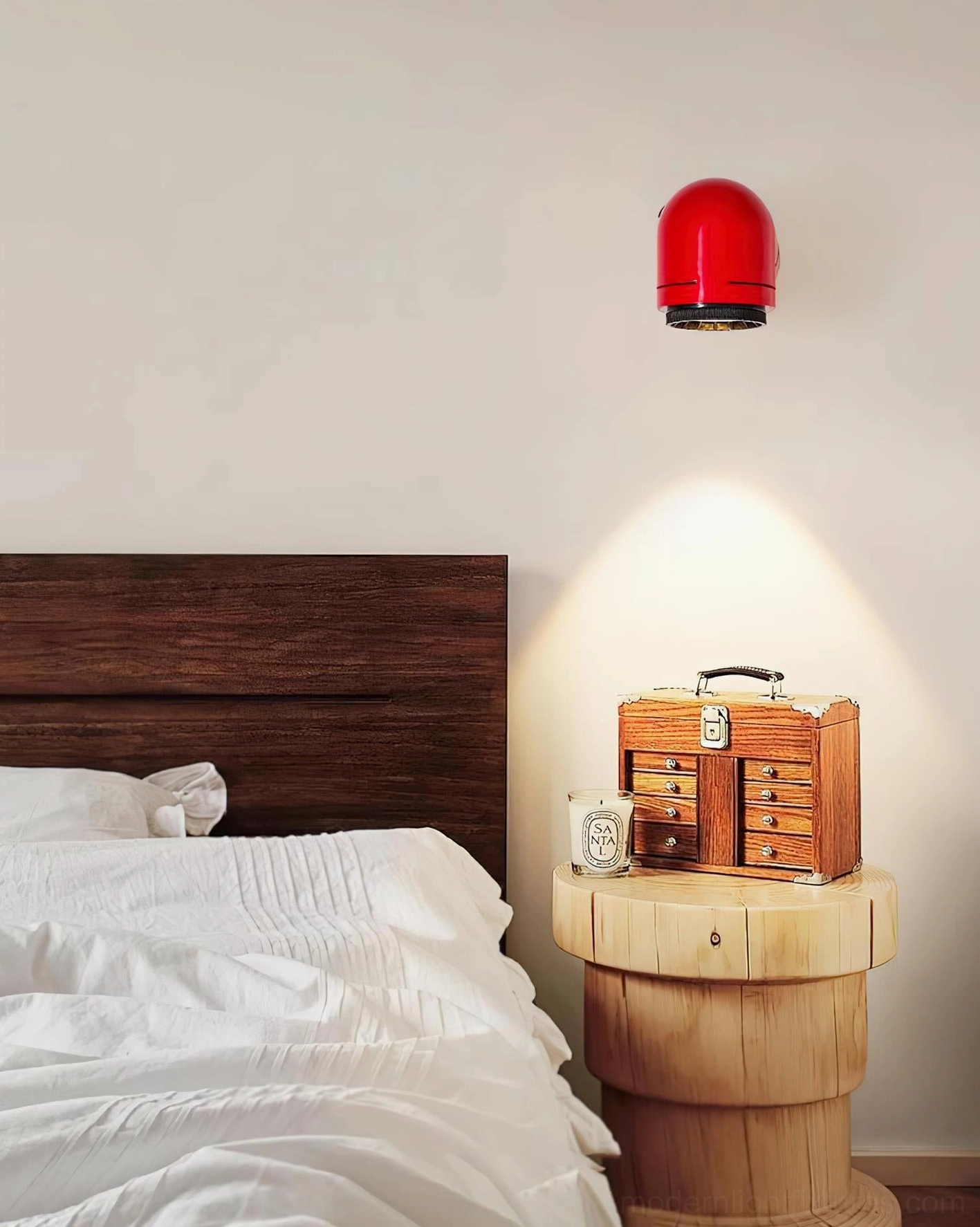 Red cylindrical wall sconce positioned above wooden nightstand in bedroom with warm atmospheric lighting