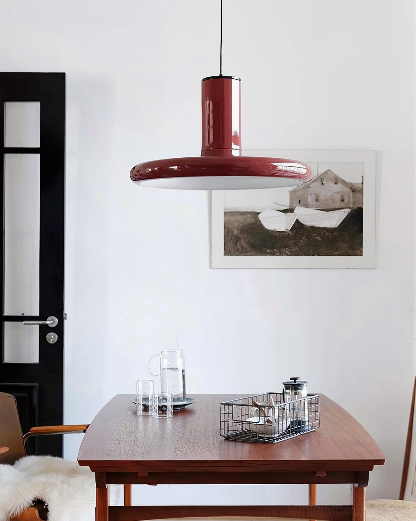 Modern red disc pendant light suspended above formal dining room wooden table