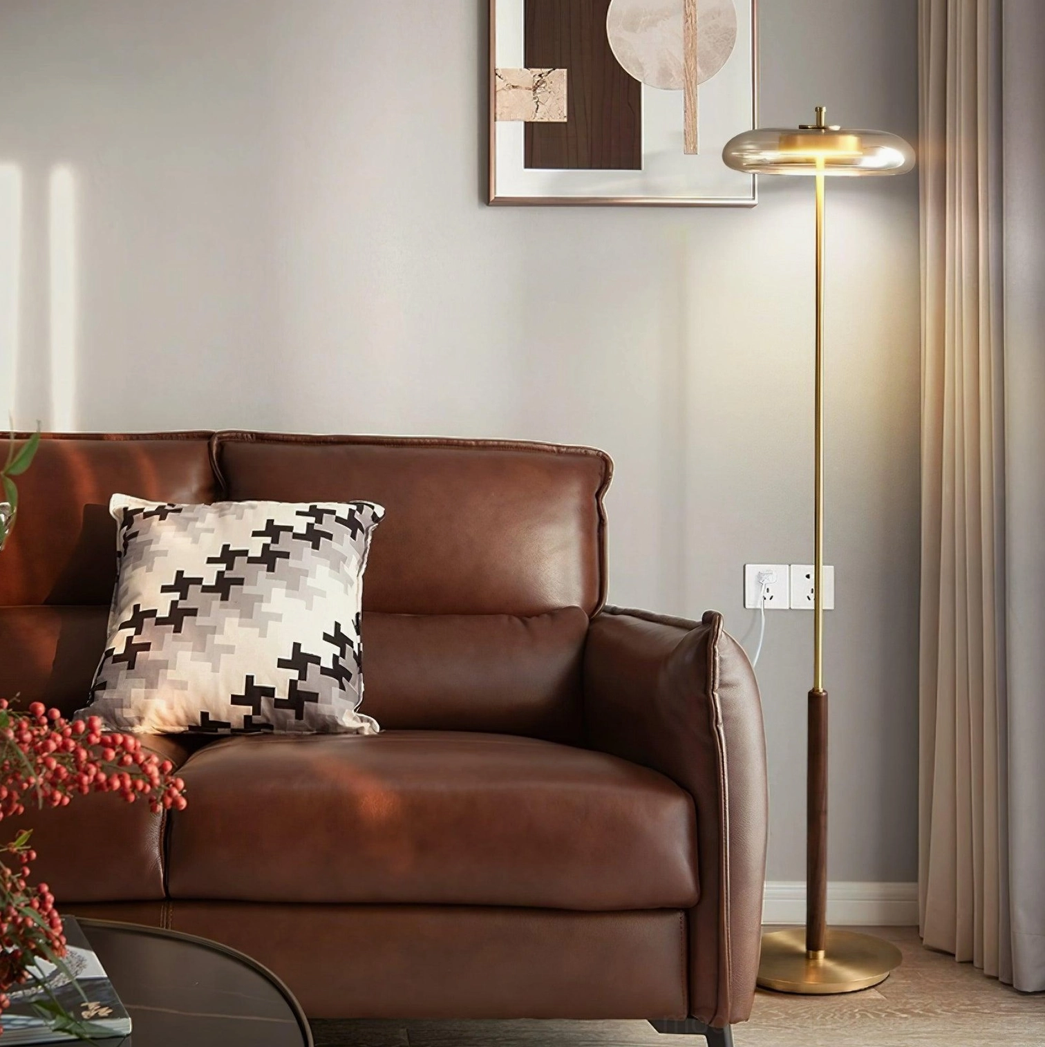 Redondo modern floor lamp with brass pole and walnut section beside brown leather sofa in contemporary living room setting