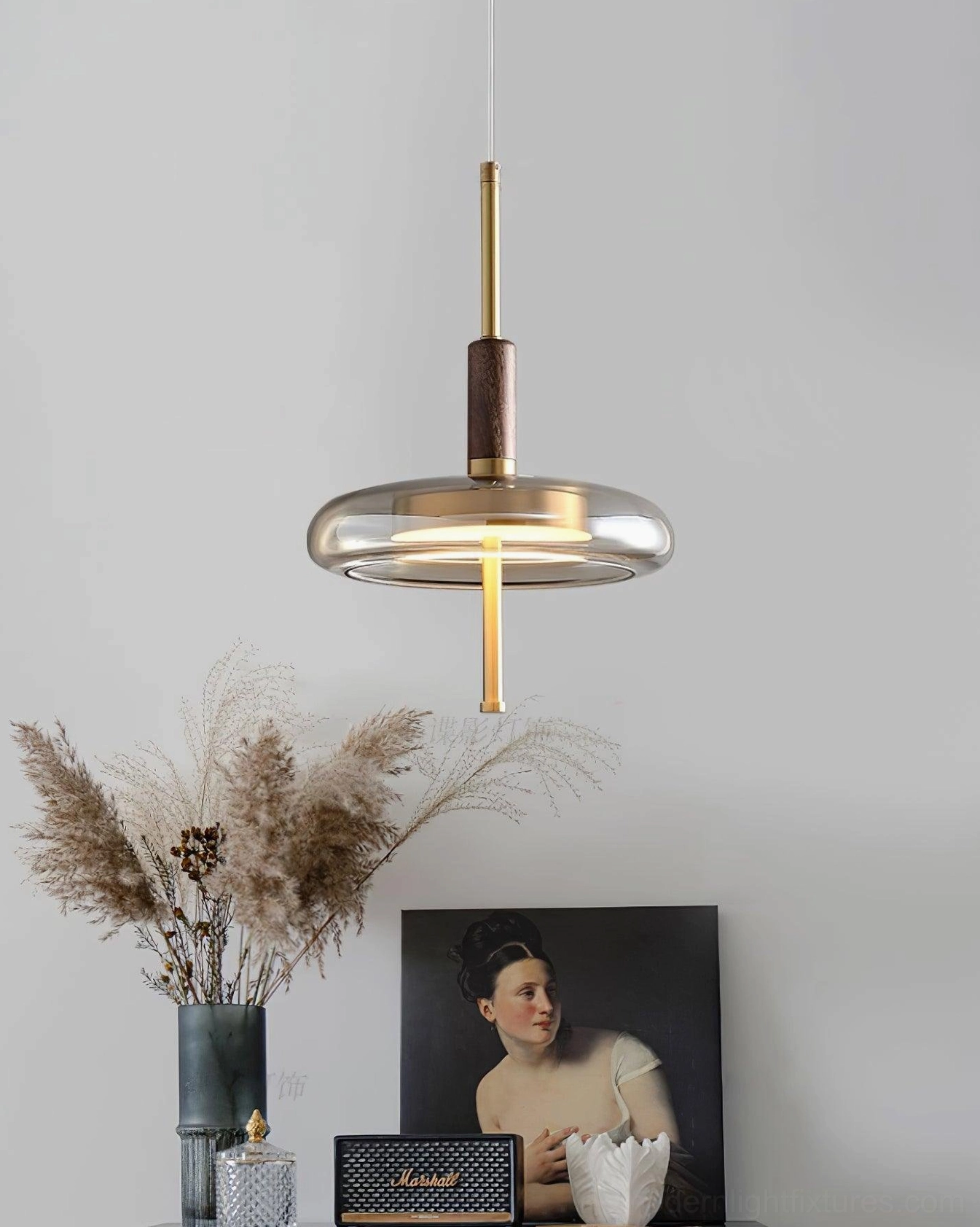 Redondo pendant fixture detail view showing brass components, amber glass dome, and warm light output