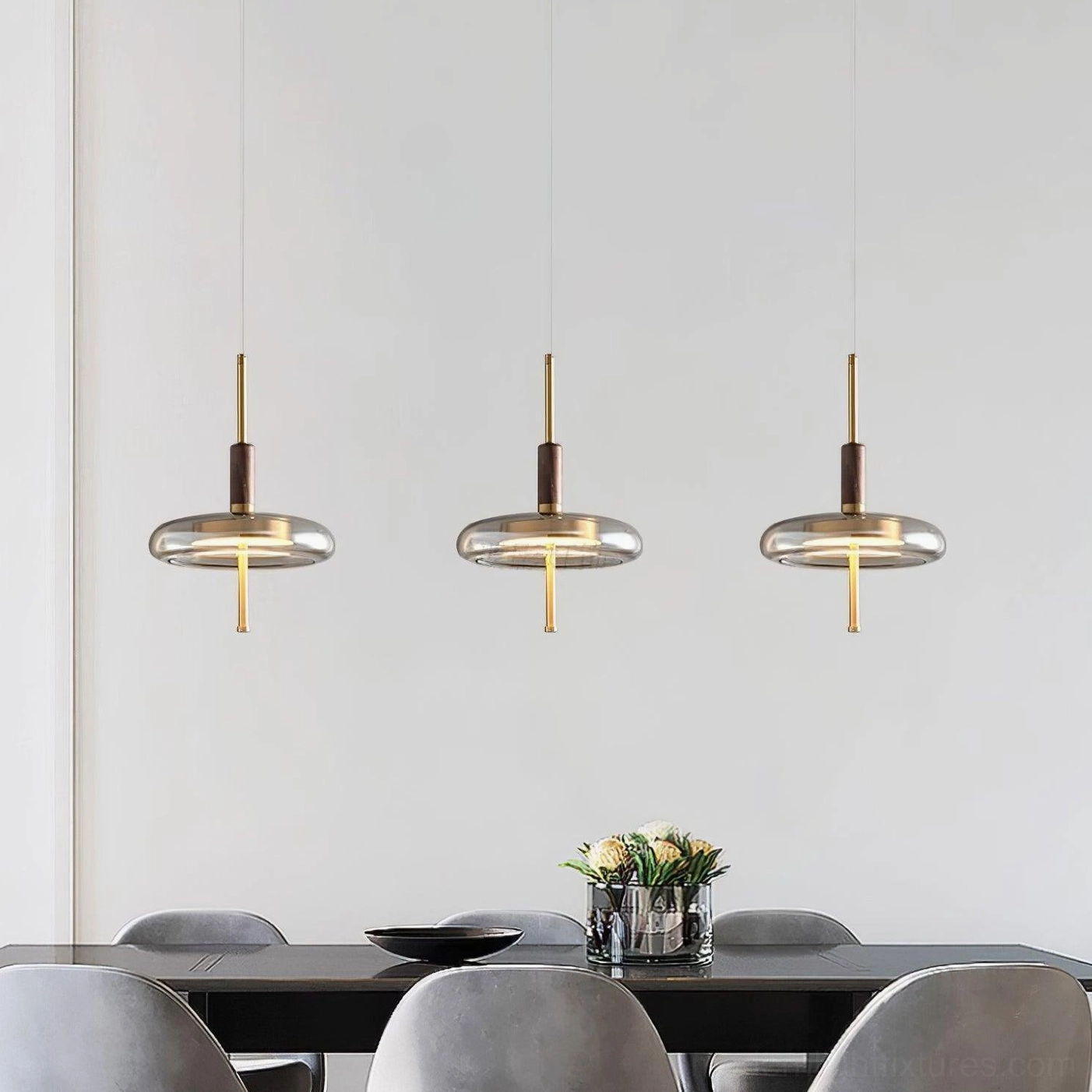 Triple Redondo pendant lamps hanging above black dining table in residential dining room, creating warm ambient lighting