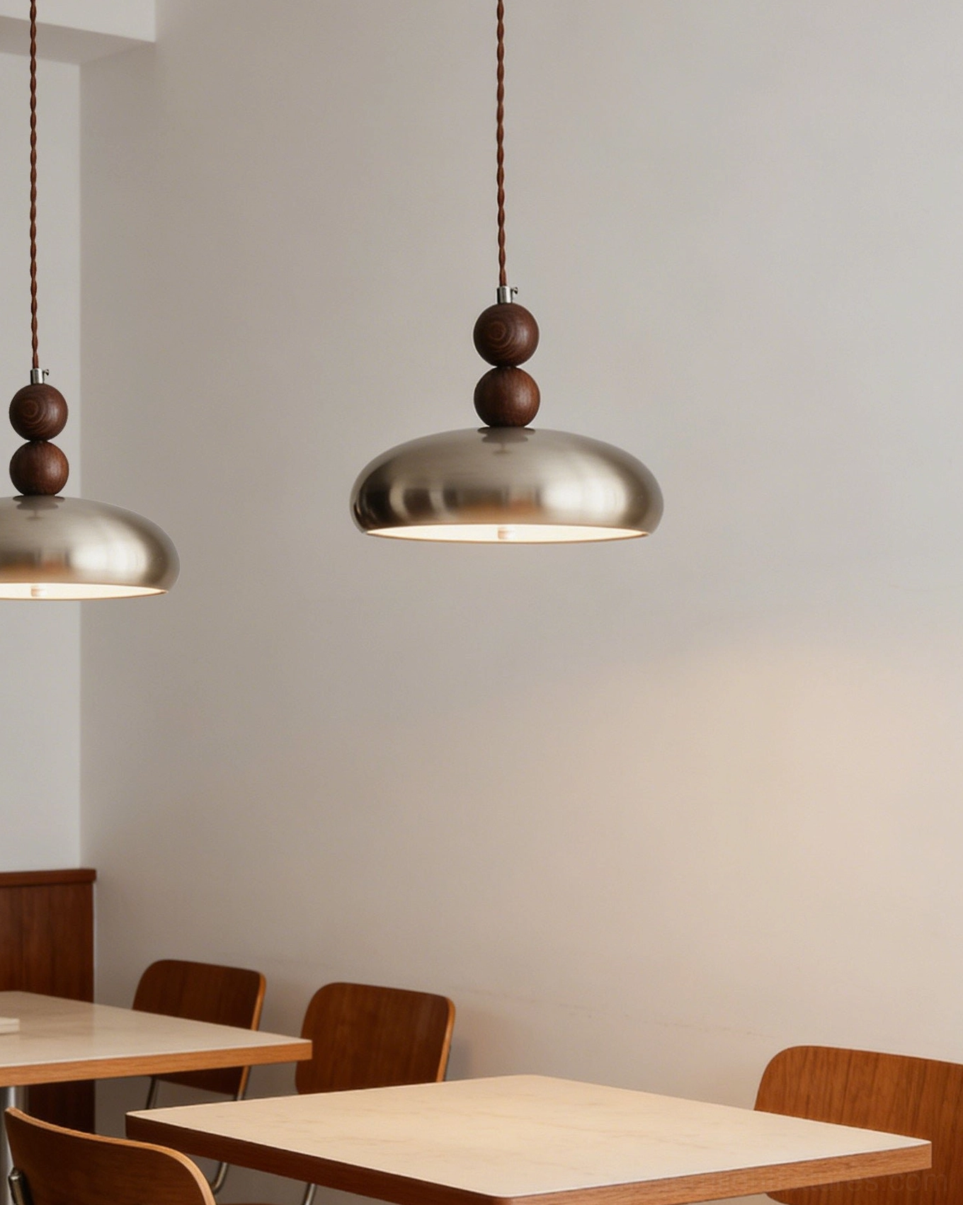 Pair of matching Rellin pendant lamps in minimalist restaurant dining space with uniform brushed metal shade design