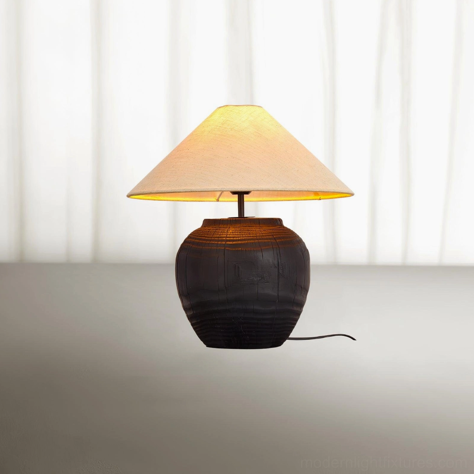 Close-up of illuminated black resin table lamp with power cord near window