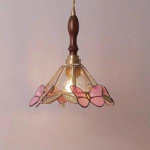 Vintage butterfly pendant light hanging in three-quarter view showing warm pink stained glass shade, visible E14 bulb socket, and brass-walnut fixture assembly