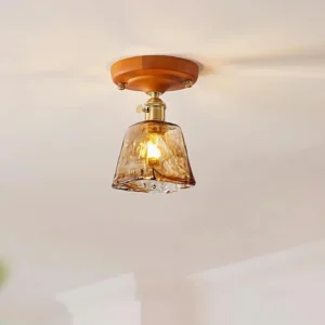 Close-up overhead view of retro glass ceiling light fixture with amber textured shade and brass base, neutral background