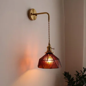 Vintage tiffany style wall sconce installed in corner with amber glass shade casting warm light and green foliage backdrop