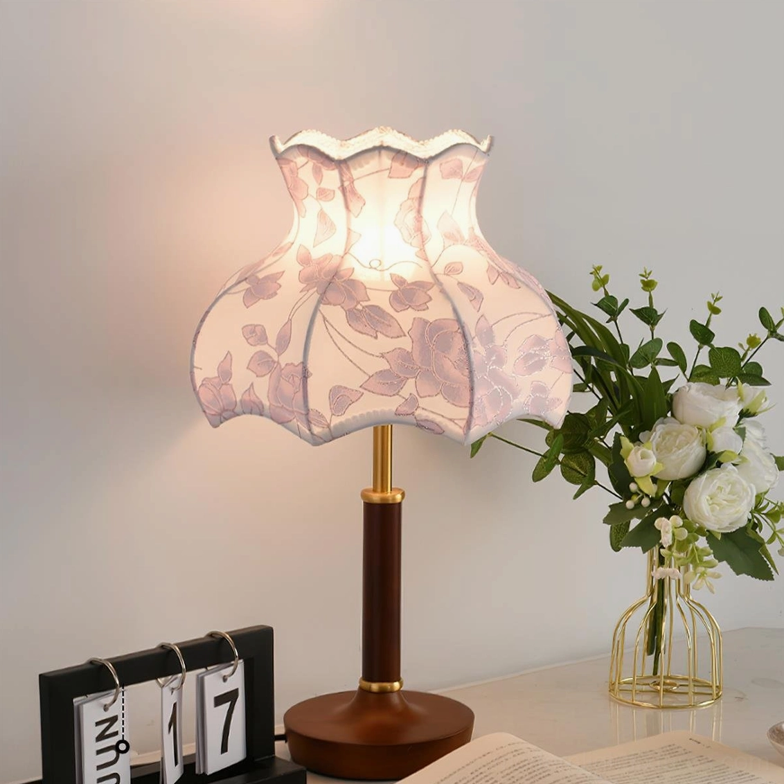 Retro pink floral table lamp with scalloped edge shade and walnut wood base, displayed on home desktop with flower vase