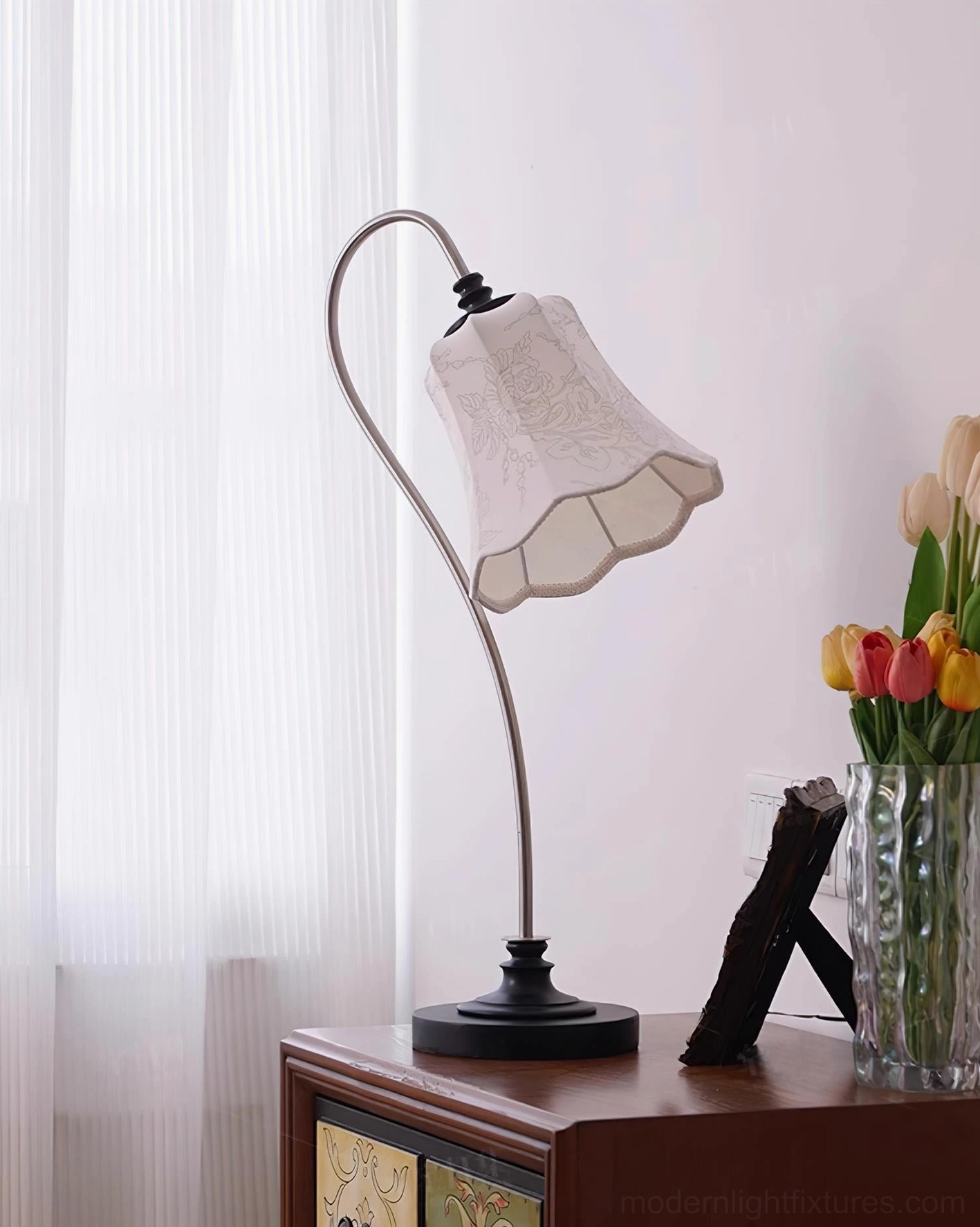 Retro table lamp on home side table with decorative flowers vase and stacked books arrangement