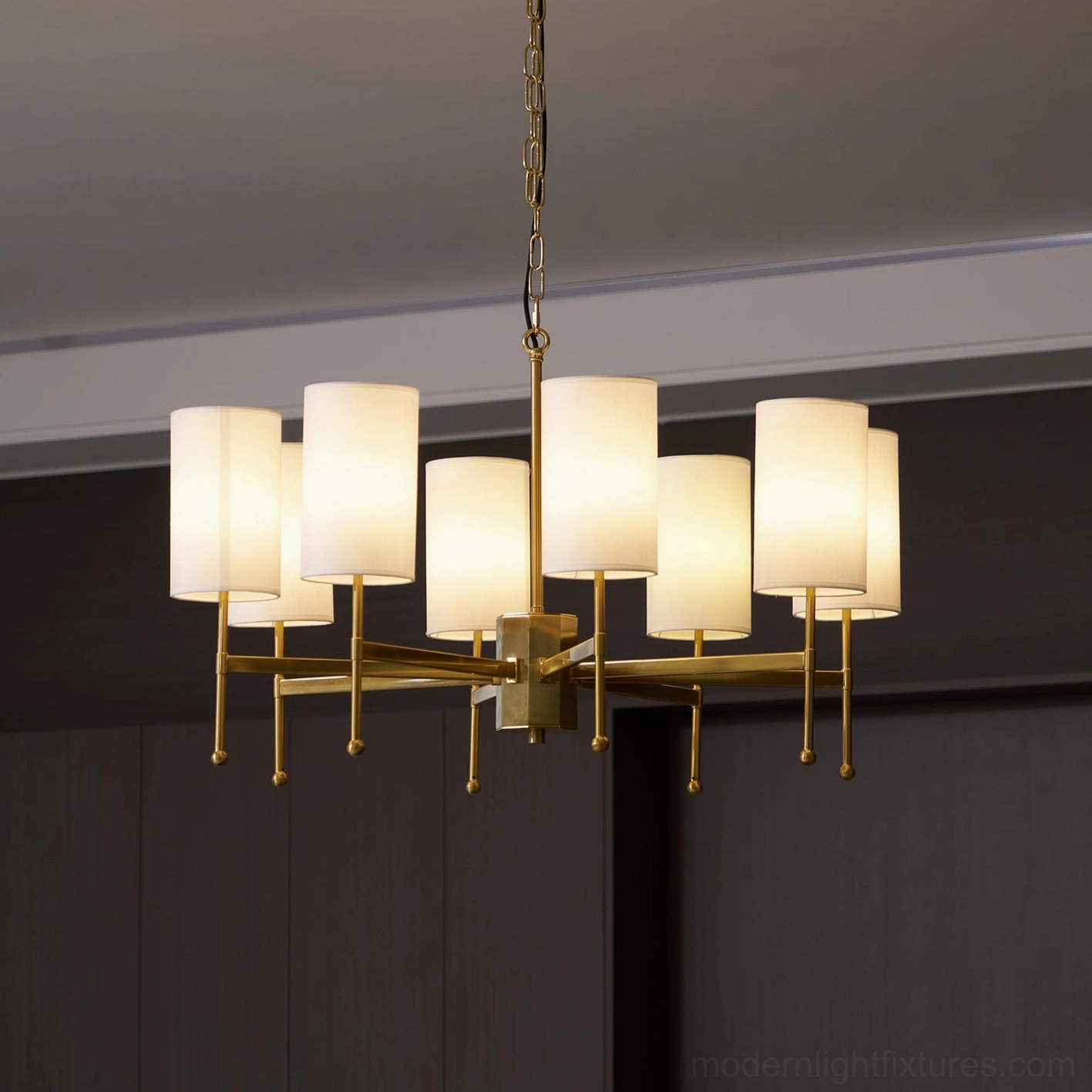 Illuminated Rhodes mid-century modern chandelier with warm glowing white fabric shades and brass frame - studio photography