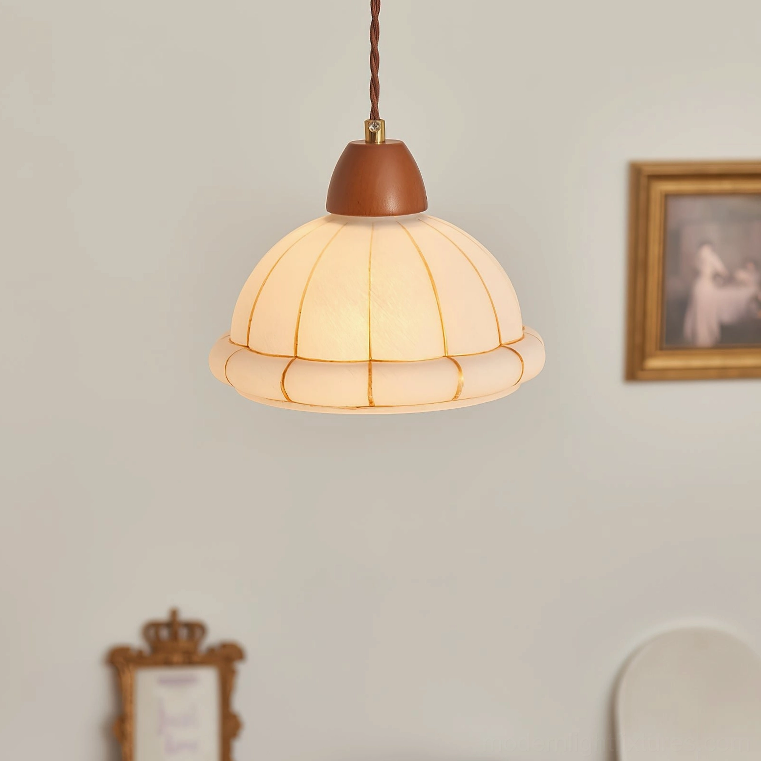 Kaya glass pendant shade with amber accent details and gold trim, low-angle view with wall art backdrop