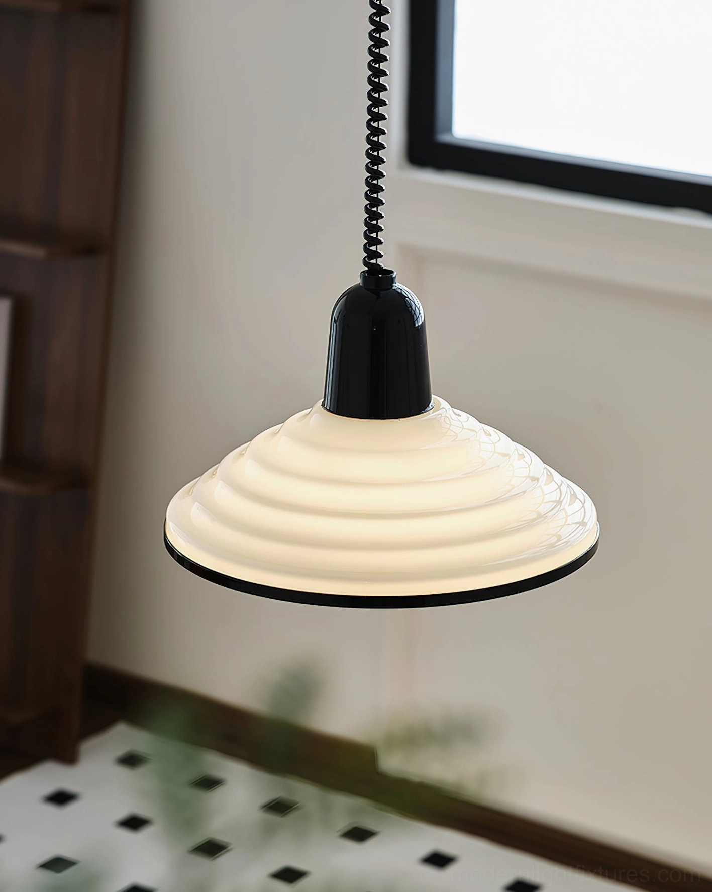 Black and white ribbed pendant lamp with black trim in low frontal view, hanging above checkered tile floor with retro industrial aesthetic
