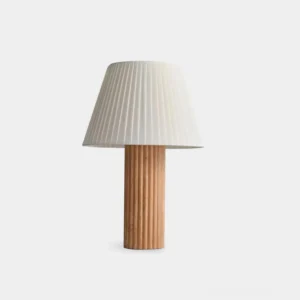 Modern ribbed wood table lamp with white pleated fabric shade on minimalist white background, front studio view showcasing wabi-sabi design aesthetic