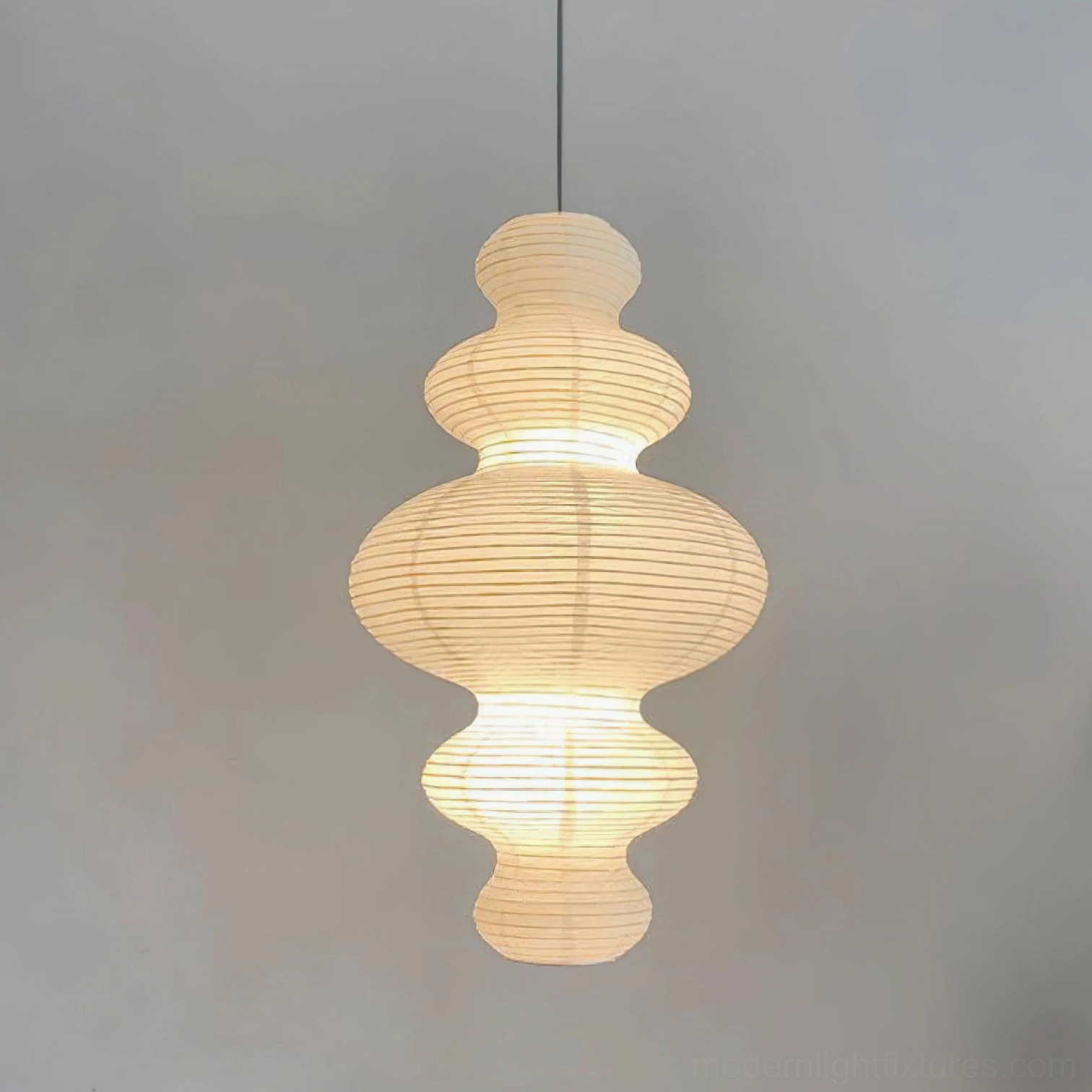 Close-up front view of ribbed rice paper pendant light showing warm glow and texture detail