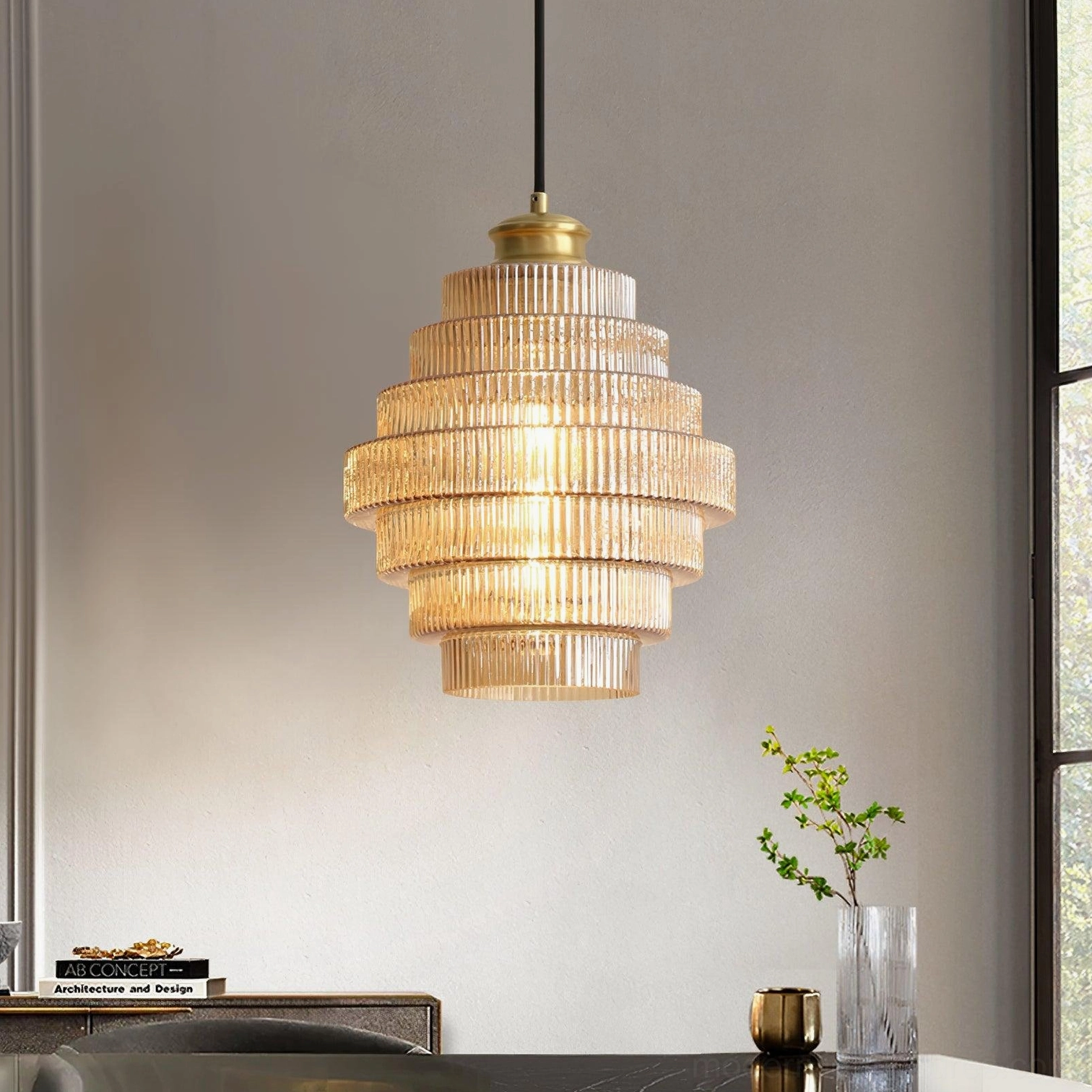 Tiered glass pendant light hanging above dining table with decor and plants, three-quarter view
