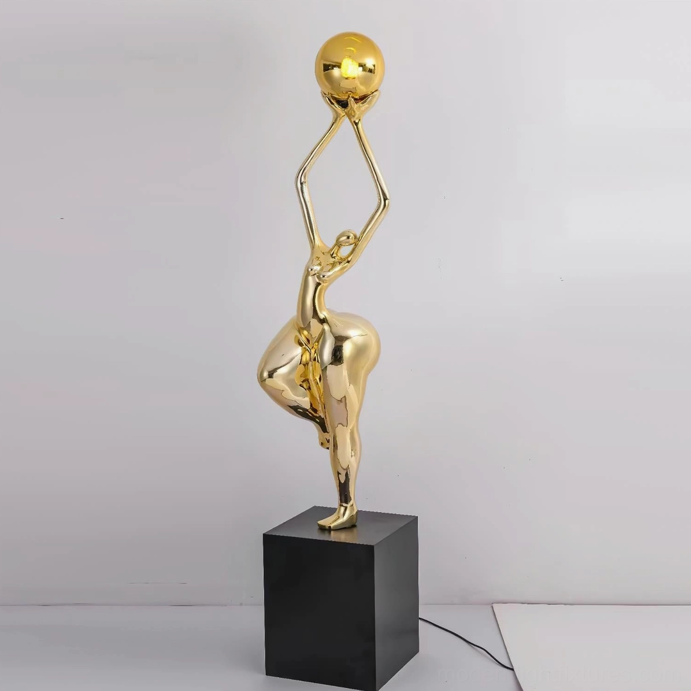 Polished gold female sculpture floor lamp with square pedestal and golden glass sphere against white studio background