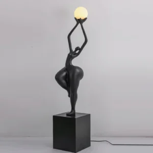 Contemporary female form sculpture floor lamp in black with square pedestal base and minimalist interior setting, artistic lighting fixture