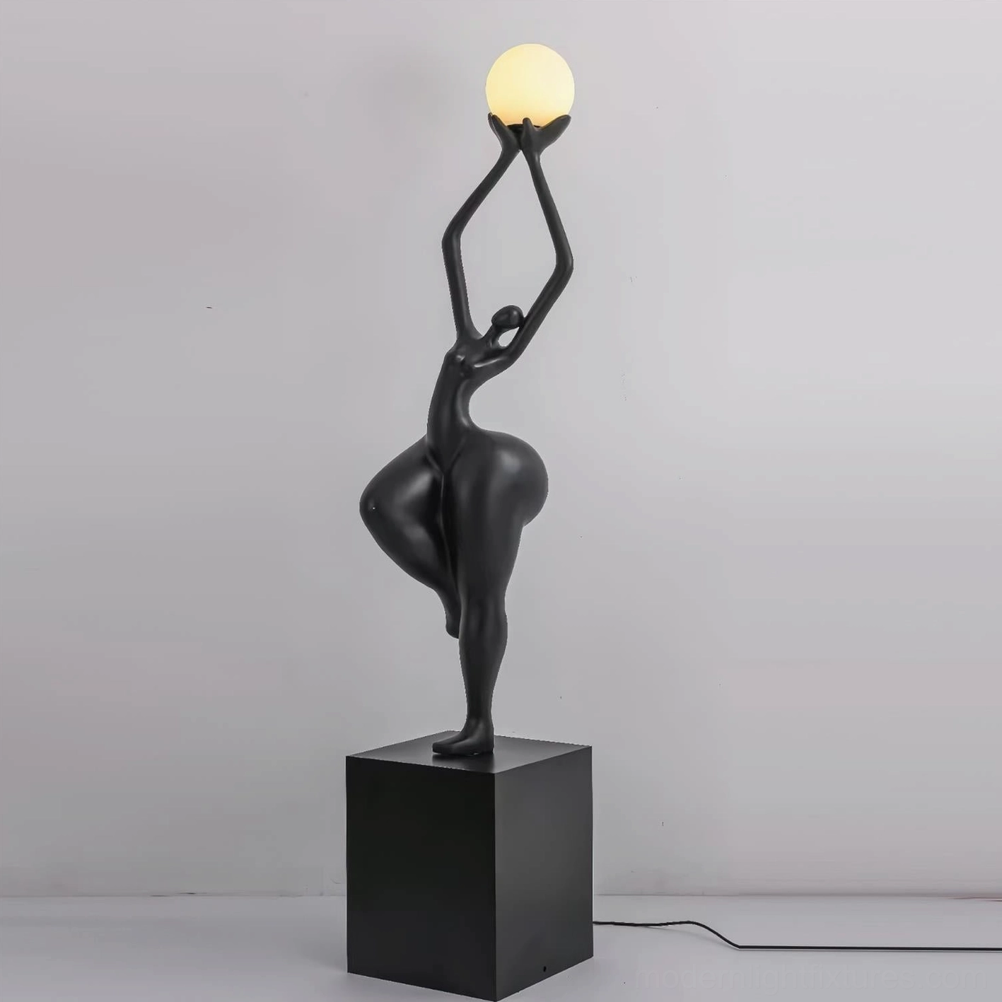 Contemporary female form sculpture floor lamp in black with square pedestal base and minimalist interior setting, artistic lighting fixture