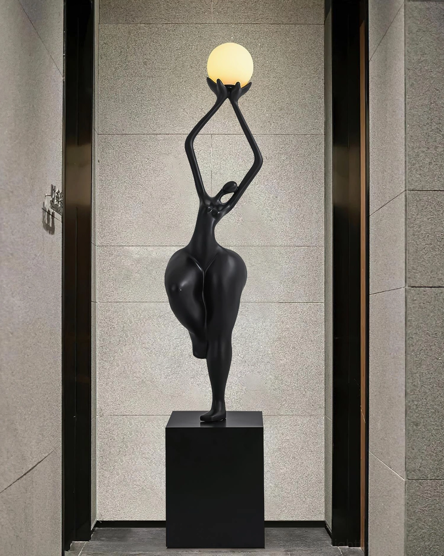 Black abstract female sculpture floor lamp with square pedestal in stone-clad foyer, modern art lighting fixture