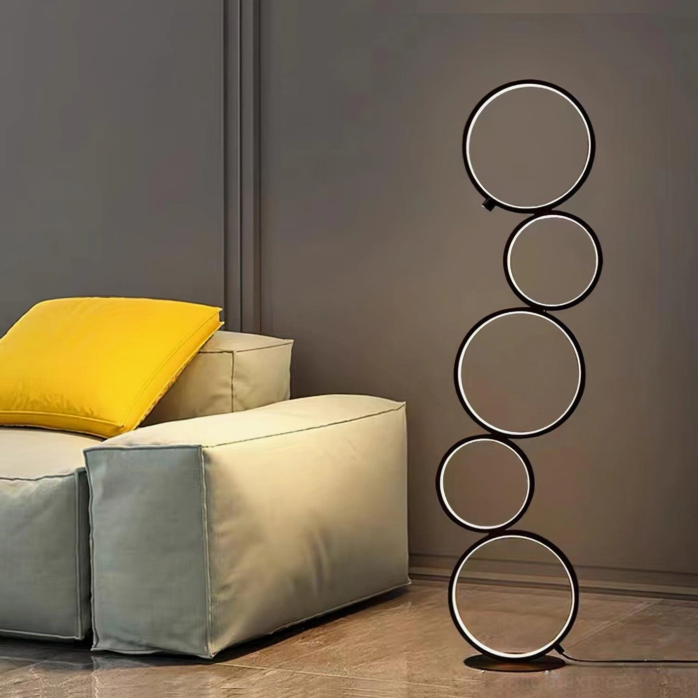 Minimalist ring floor lamp in black beside light gray fabric sofa in residential living room setting