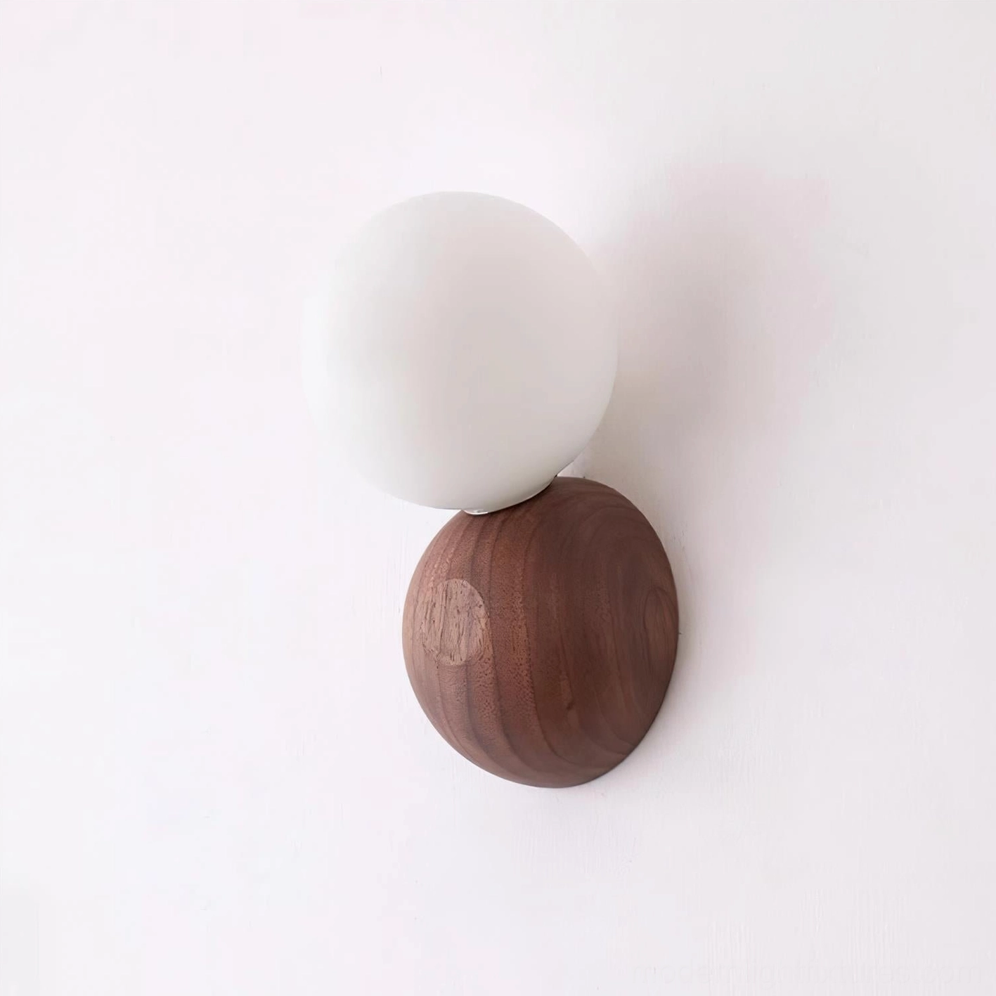 Ringo wall sconce side angle view showing profile of wood base and spherical glass shade in warm minimalist setting