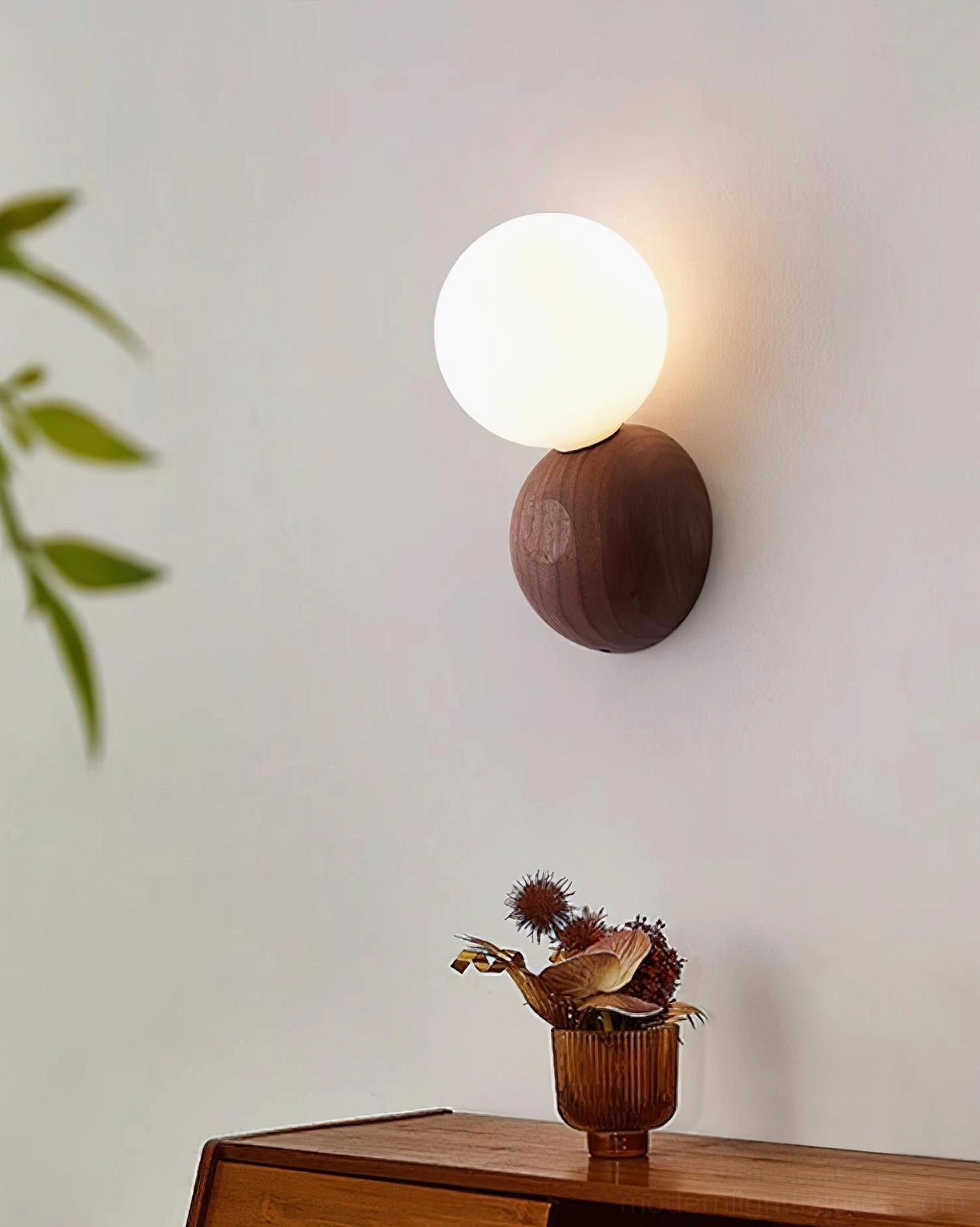 Ringo hardwired wall sconce on bedroom wall beside wooden nightstand with potted plants and dried flowers