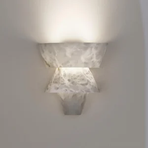 Rinkle alabaster wall lamp installed at eye level casting warm ambient light on neutral wall