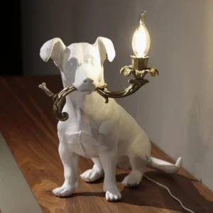 Rio dog table lamp on wooden desk, decorative canine-shaped light fixture interior setting, white resin with gold accents seated position