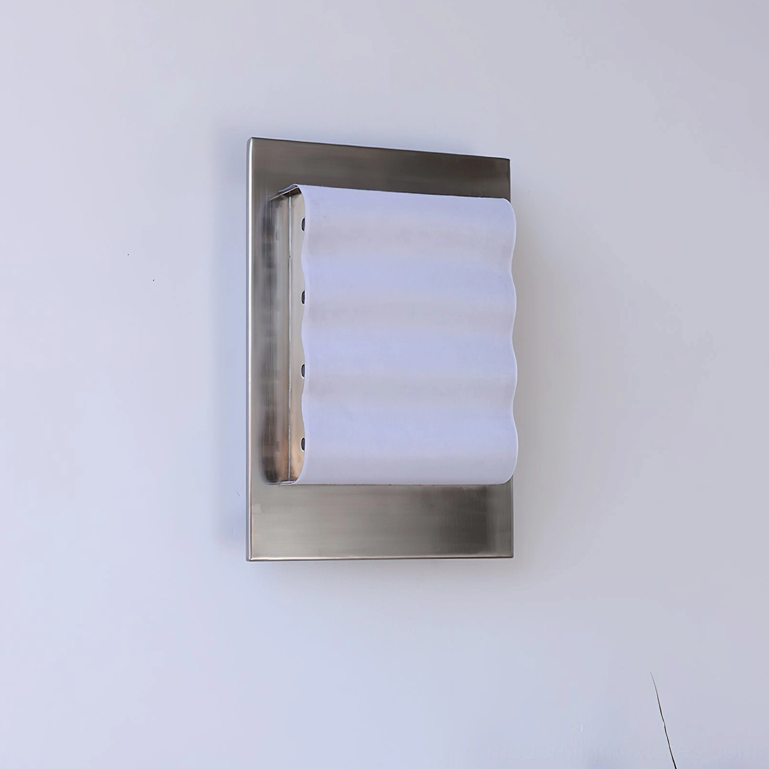 Ripple edge wall sconce mounted beside dried floral decor showing brushed silver frame and warm glow